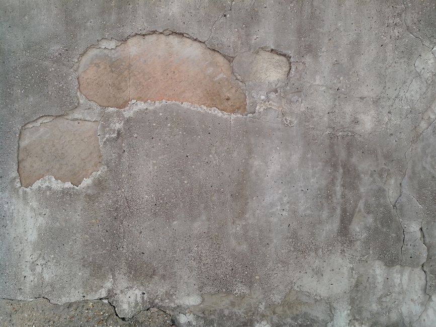 A worn interior wall with patched and bare areas.
