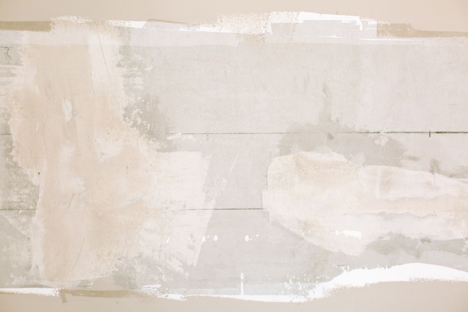 Close-up of an unfinished wall showing plaster and paint textures in a home renovation.